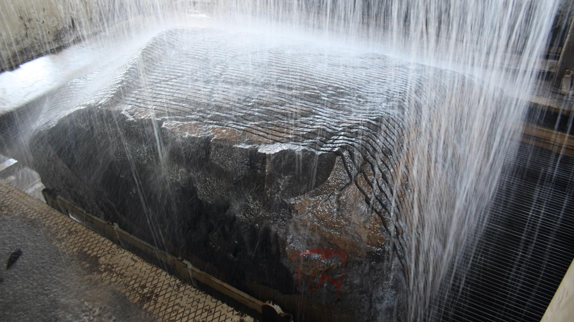 Basaltblock im Gattersäge-Rahmen, Wasser läuft über die Schnittfläche